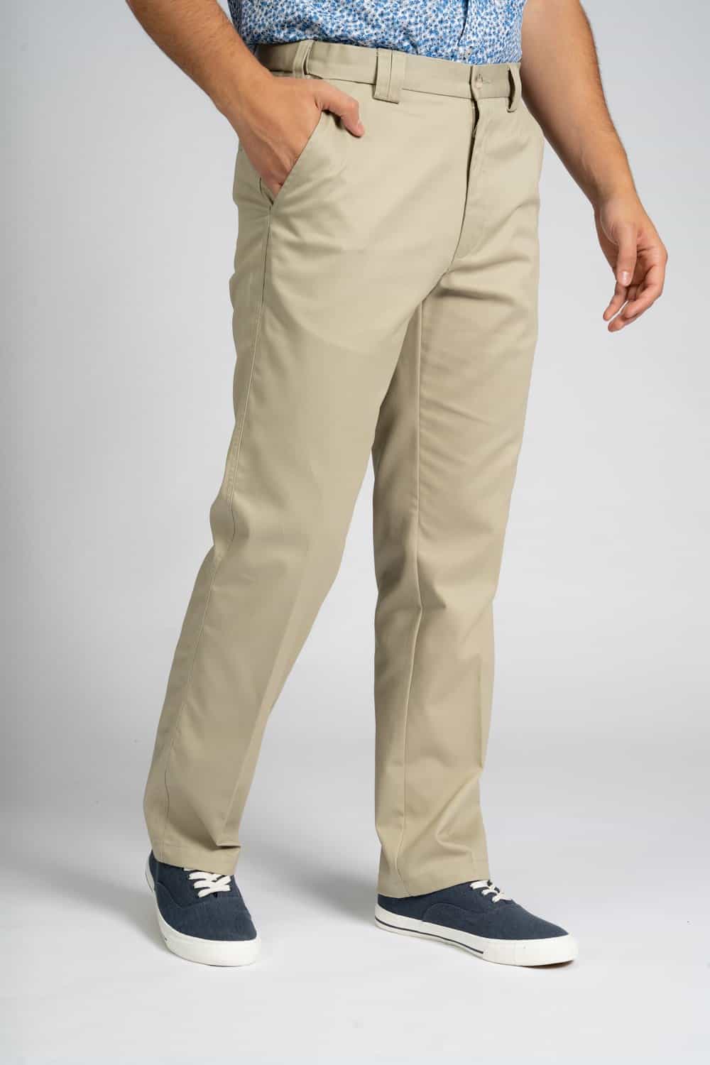 Full-length view of a person wearing beige straight-leg chinos with a blue patterned shirt tucked in, one hand in the pocket, paired with blue lace-up sneakers.