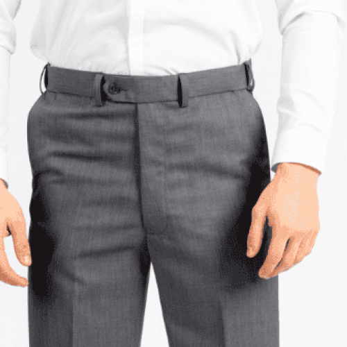 A cropped studio-style image showing the torso and upper legs of a person wearing a crisp white dress shirt tucked into tailored medium-gray dress trousers. The pants have a flat front, belt loops, and a button closure, giving a polished formal or business look. The background is plain light gray, with soft lighting that highlights the clean lines of the outfit.